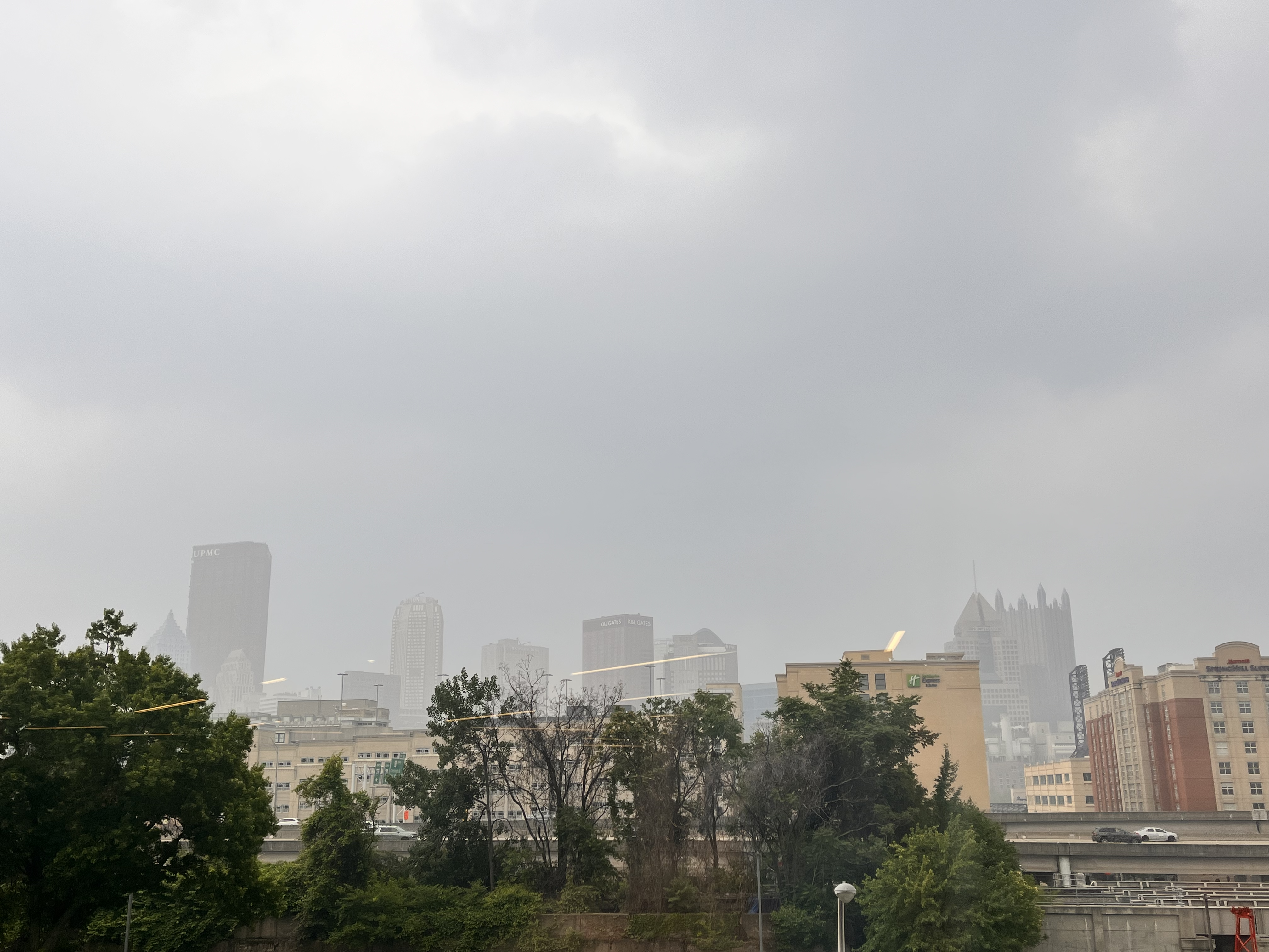 View of Pittsburgh's city skyline barely visible through grey wildfire smoke.
